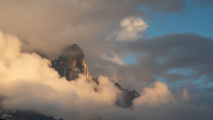 Aiguille du Moine with ridge and blue sky during sunset surrounded by heavy clouds in warm light