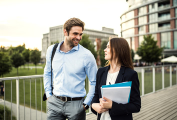 A young businessman and businesswoman walking on a bridge.
