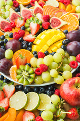 Variety of healthy raw fruits and berries background, strawberries raspberries oranges plums apples kiwis grapes blueberries, mango, vertical, selective focus