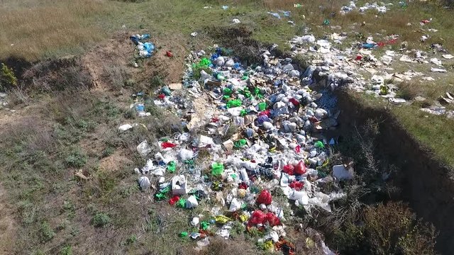  People threw garbage outside the city into the pit. All this pollutes the environment. Many multicolored packets - red, green, blue, white. The wind pumps the grass that grows here.