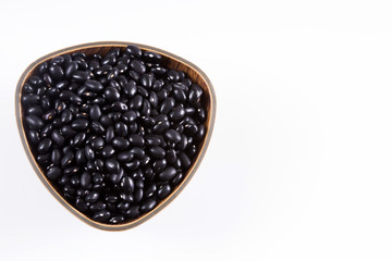 Raw black beans on the wooden background