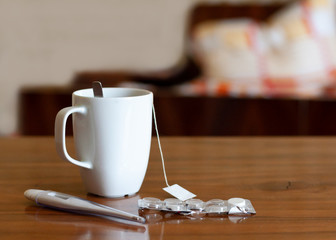 Fieber, Tee, Thermometer, Lutschtabletten mit einem Krankenbett im Hintergrund, Schlafzimmer, krank