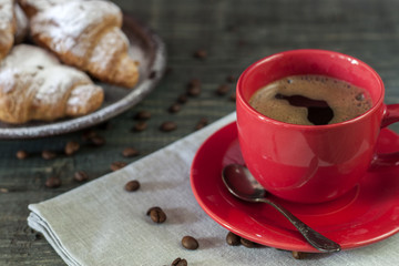 Cup of cappuccino coffee and croissant on dark table