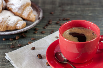 Cup of cappuccino coffee and croissant on dark table