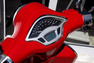 Fototapeta premium Red front handlebars of a motor scooter moped motorbike with speedometer - concept design transport lifestyle traffic famous