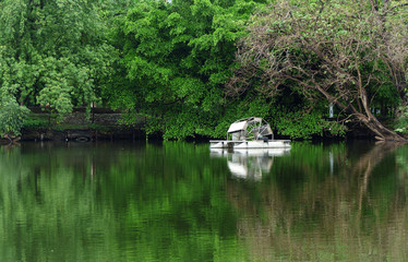 Fototapeta na wymiar Metal water wheel floating on the lake of park