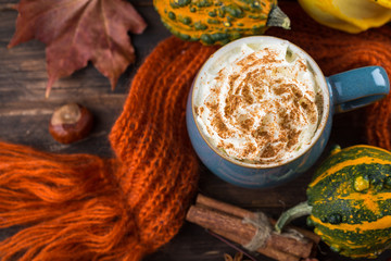 Pumpkin latte with spices and whipped cream on top on a wooden background. Copy space. Autumn or winter hot drink.