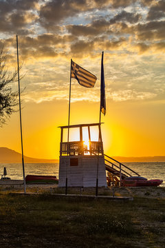 Early morning, dramatic sunrise over sea and house for rescuers on the beach.