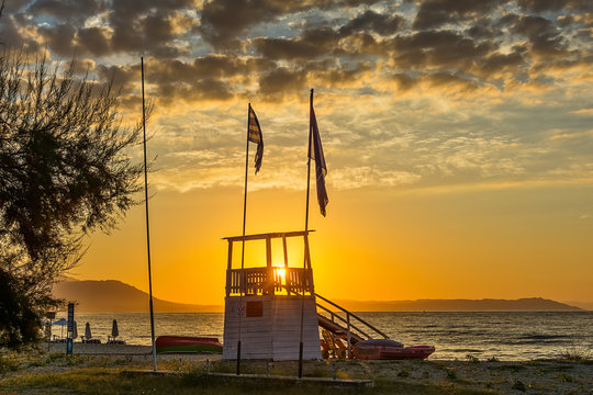Early morning, dramatic sunrise over sea and house for rescuers on the beach.