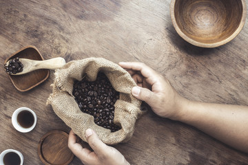 The coffee beans into the cup wood, placed on a wooden floor.