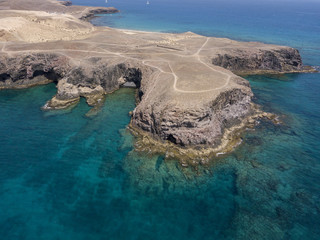 Vista aerea delle coste frastagliate e delle spiagge di Lanzarote, Spagna, Canarie. Strade e sentieri sterrati. Bagnanti in spiaggia. Oceano Atlantico. Papagayo