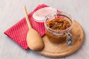 Jar of chutney of apples and vegetables on a gray table.