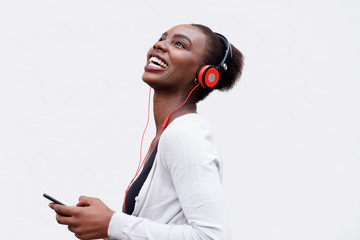 Profile of happy young african american woman listening to music with smart phone and headphones