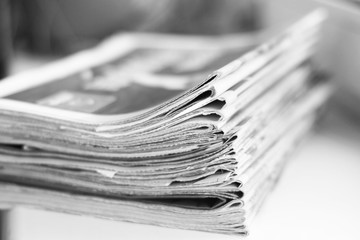 Pile of fresh morning newspapers on the table at office. Latest financial and business news in daily paper. Pages with information (headlines, articles, photos, text). Folded and stacked journals