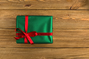 Green gift with red ribbon, Christmas tree and decorations on the table. New year.