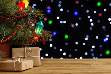 Craft gifts under the tree, on the table, against the background of blurry lights, bokeh. The concept of Christmas and New Year.