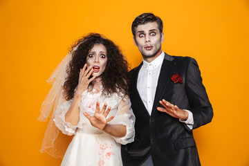 Photo of terrifying zombie couple bridegroom and bride wearing wedding outfit and halloween makeup...
