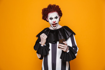 Happy clown using smartphone and making winner gesture