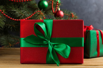 Green red gifts under the tree, on the table, against the wood background. The concept of Christmas and New Year.