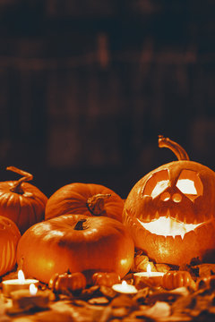 Vertical view of Halloween pumpkin lanterns amongst candles, real photo with copy space on the black background