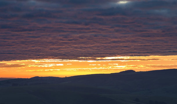 Colorful Sunrise Clouds over Hilly Countryside