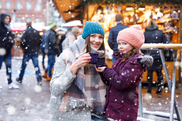 Young woman and cute kid girl with cup of steaming hot chocolate or children punch