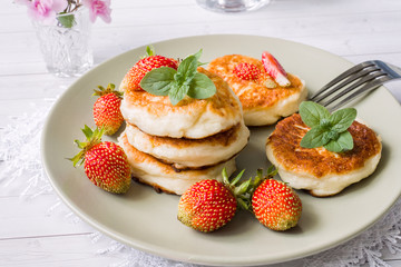 Curd pancakes with strawberries and mint on a plate