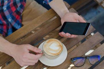 Phone in hand and a Cup of coffee.