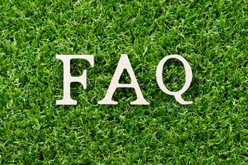 Wood letter in word FAQ (Abbreviation of Frequently asked questions) on artificial green grass background