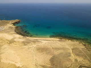 Vista aerea delle coste frastagliate e delle spiagge di Lanzarote, Spagna, Canarie. Strade e sentieri sterrati. Bagnanti in spiaggia. Oceano Atlantico. Papagayo