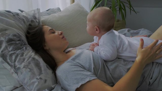 Mother and her Newborn Baby. Happy Mother and Baby kissing and hugging. Resting in bed together. Maternity concept. Parenthood. Motherhood Beautiful Happy Family Stock Video Footage