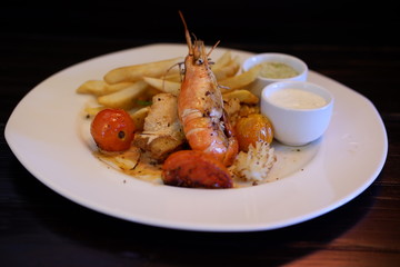 mixed grilled seafood and french fries on wood table