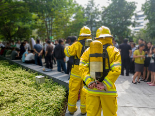 Select focus of back Firefighters in yellow suit with an oxygen tank in the back. Firefighters are teaching office workers to escape from high-rise buildings (Fire Drill).