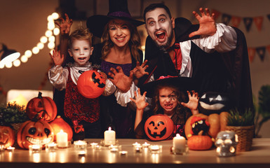 happy family mother father and children in costumes and makeup on a celebration of Halloween in dark home.