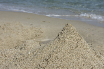 Abstract sandy castle on the beach. Close up view. Selective focus. Copy, negative space. Natural texture background