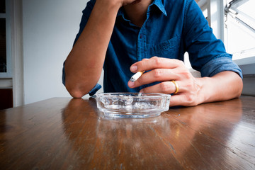 Man in blue shirt keep cigarette in hand