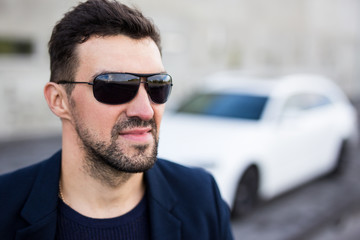 close up portrait of handsome man in sunglasses with his car
