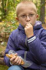 baby eats in the fall forest,a schoolboy in the forest eats cheese