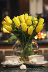 A bouquet of yellow tulips in a vase in the interior of a retro 