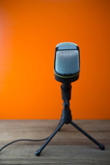 modern microphone with orange background and wooden floor, soft focus