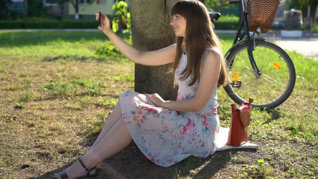 Pretty college girl taking selfies in park, posting photos in social media