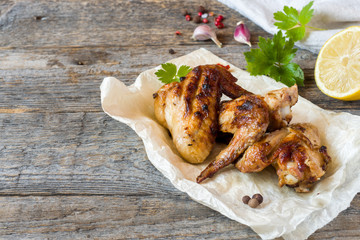 Chicken wings baked on grill with fresh herbs, lemon on wooden background.