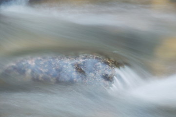 blurry water flowing on the rock and wave splashing in river