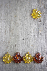 Yellow and orange glass leaves on rustic wooden background with copy space