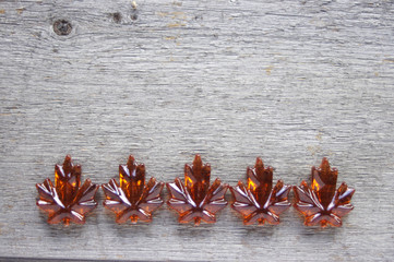 Orange glass maple leaves on rustic wooden background with copy space
