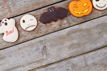 Halloween holiday cookies on wooden background. Halloween homemade gingerbread biscuits with icing, copy space.