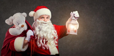 Santa Claus with a bag and a  lamp on a Christmas copyspace background.