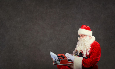 Santa Claus writes a letter on the a typewriter on gray background.