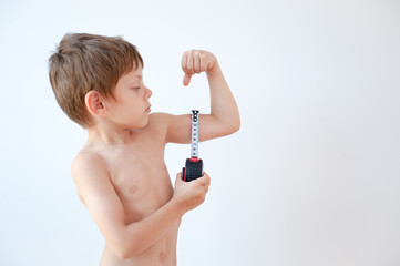healthy strong little boy measuring his muscle with tape on bright background