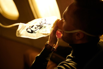 Side view portrait of unrecognizable man wearing oxygen mask in plane, copy space